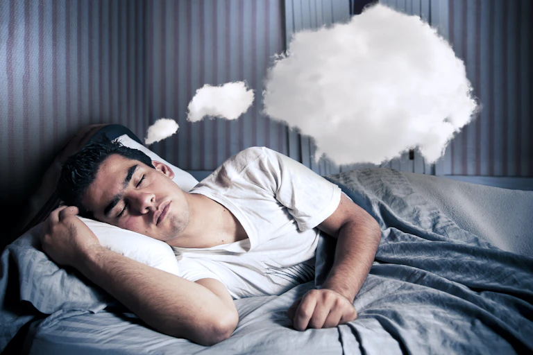 Hombre acostado durmiendo. Sobre él unas nubes representan sus sueños.