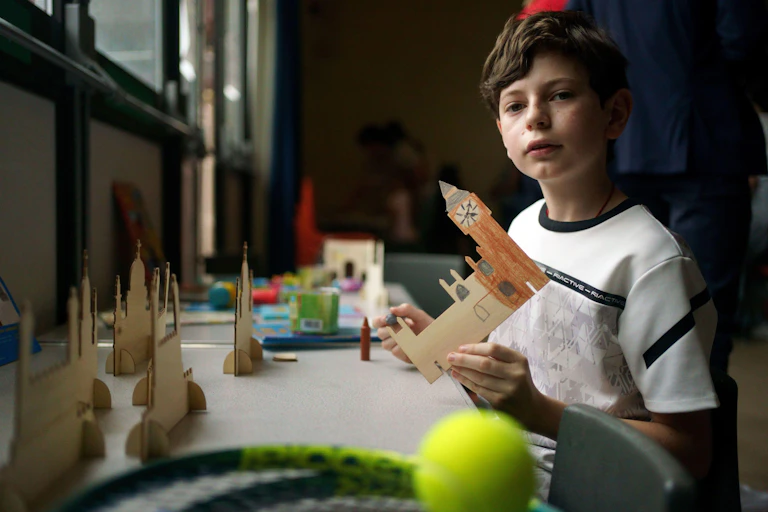 A young Ukrainian boy holds up a cardboard cut our modelof the Houses of Parliament.