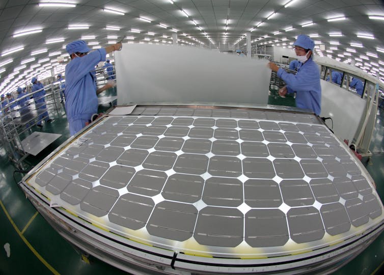 Two factory workers making a solar panel
