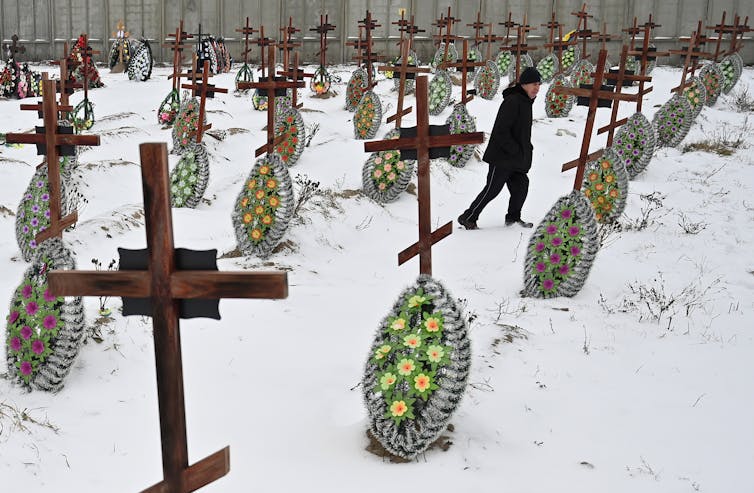 A man walks in a snowy cemetery in Bucha, Kyiv
