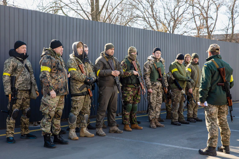 More than a dozen men dressed in camouflage holding guns lined up.