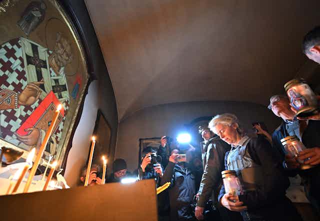 Standing amid crowds, European Commission President Ursula von der Leyen and European Union High Representative for Foreign Affairs and Security Policy Josep Borrell light candles in a Ukrainian church