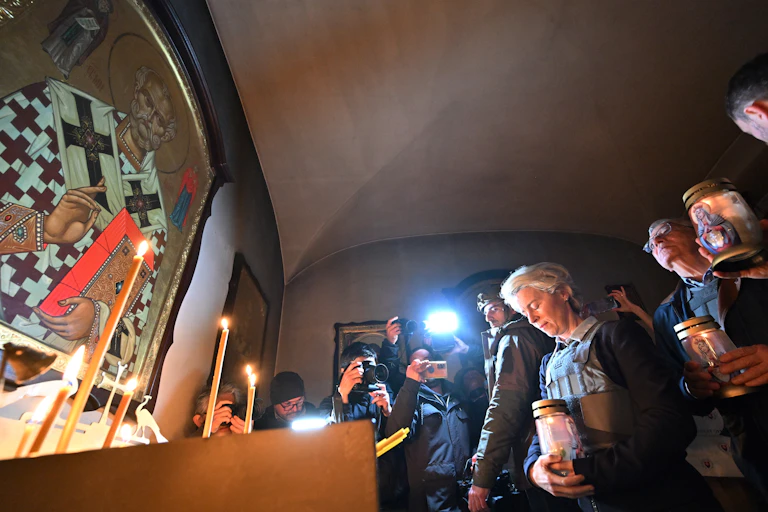Standing amid crowds, European Commission President Ursula von der Leyen and European Union High Representative for Foreign Affairs and Security Policy Josep Borrell light candles in a Ukrainian church