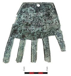 Una placa de bronce con forma de mano y cuatro líneas inscritas en ella.