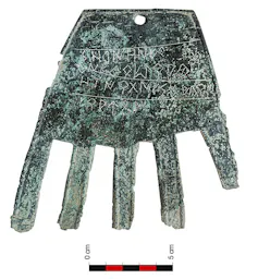 Una placa de bronce con forma de mano y cuatro líneas inscritas en ella.
