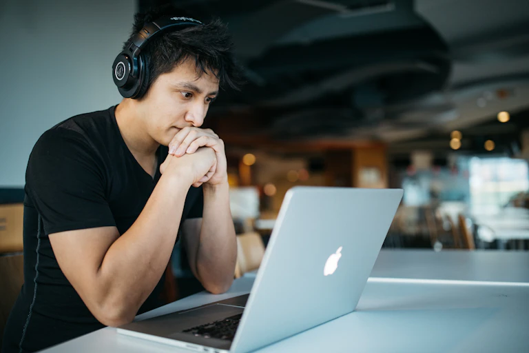A man wearing headphones works at a laptop.