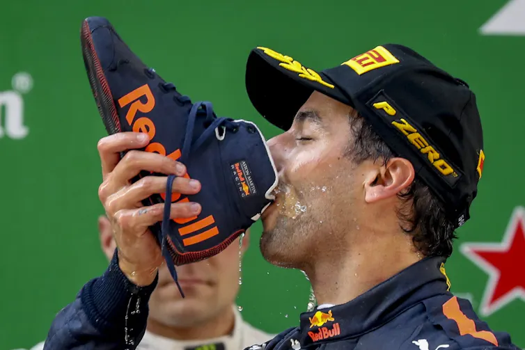 Race car driver celebrating a win by drinking champagne from a shoe