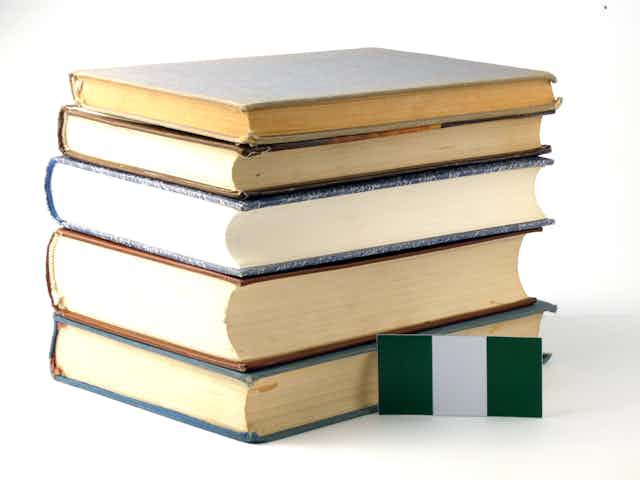 A small green and white flag lying against a pile of five books