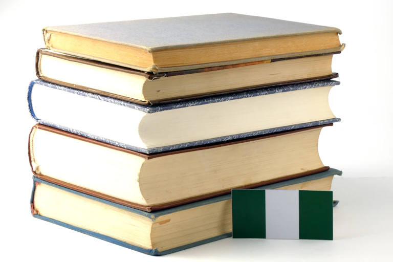 A small green and white flag lying against a pile of five books