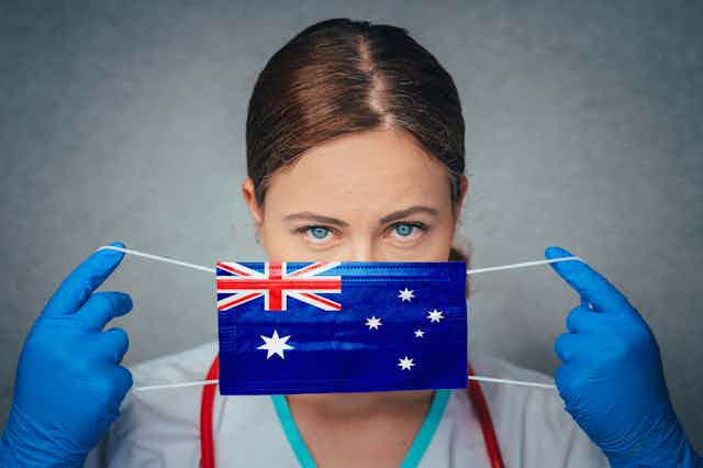 Doctor putting on a mask with the Australian flag printed on it