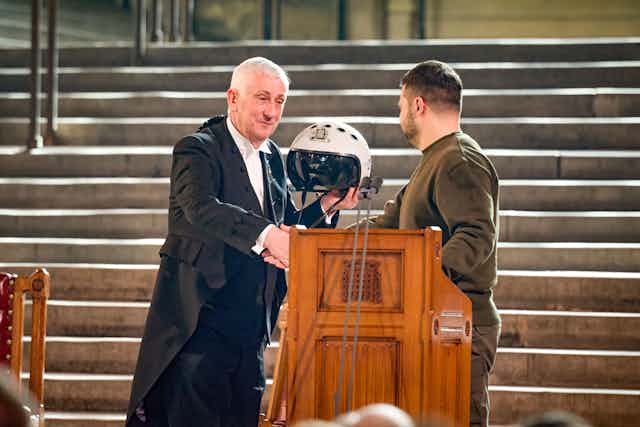 Ukraine's president, Volodymyr Zelensky, presents the speaker of the House of Commons, Sir Lindsay Hoyle, with a fighter pilot's helmet.