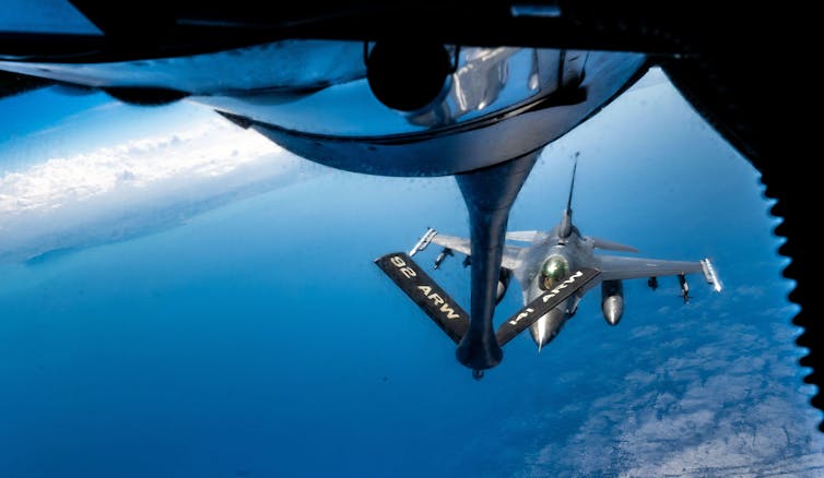 Jet fighter in flight, shot from another aircraft above.