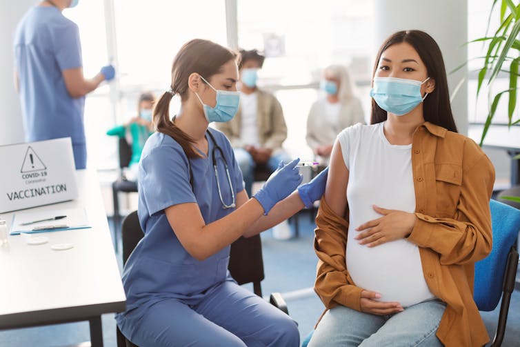 A pregnant woman receives a vaccination.