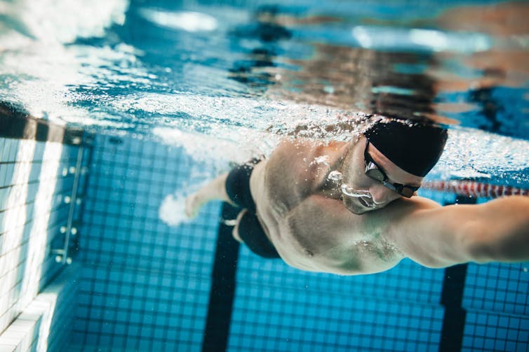 Homme nageant dans une piscine