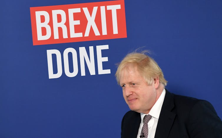Boris Johnson standing in front of a wall with the Get Brexit Done logo. The top of the text is cut off so only 'Brexit done' is visible.