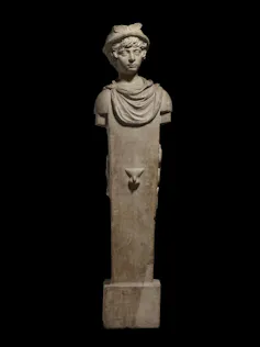 Une tête de garçon est assise sur une colonne carrée avec un pénis gravé à la hauteur appropriée