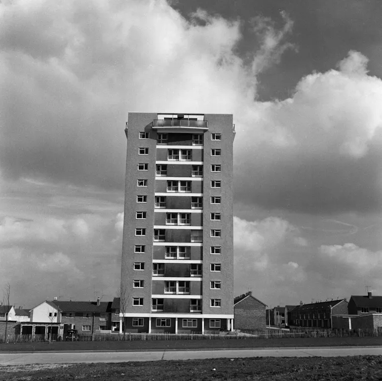 A high rise block set against a sea of clouds.