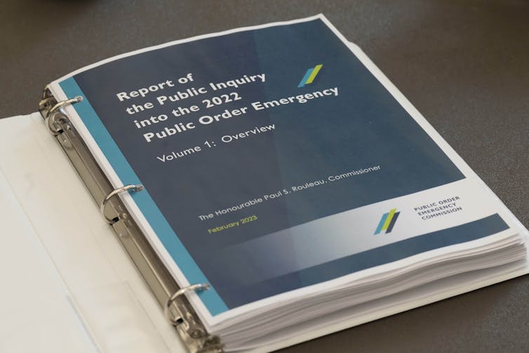 A title page that says 'Report of the Public Inquiry into the 2022 Public Order Emergency' lies in an open binder