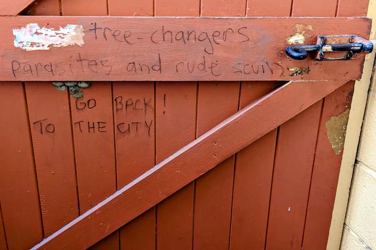 Message scrawled on gate to a property reads "Tree-changers are parasites and rude scum. Go back! To the city