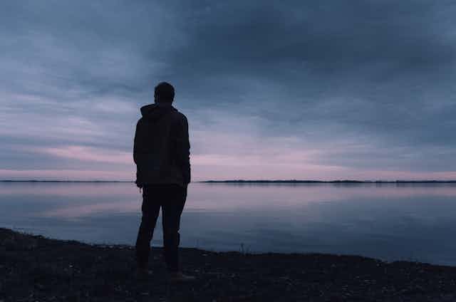 A young man looks at a lake.
