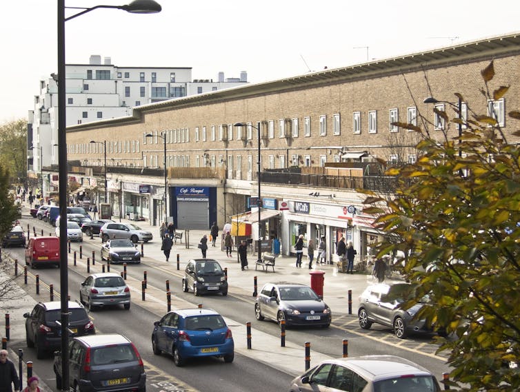 A long building with cars and shops.