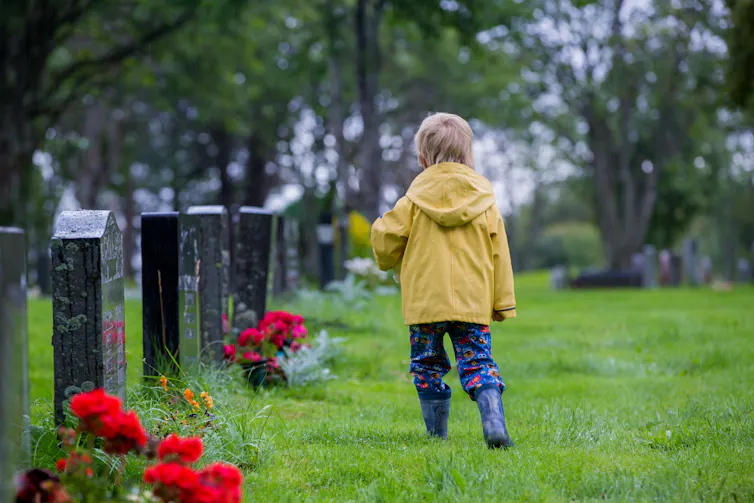 Photo d’un enfant de dos, marchant dans un cimetière