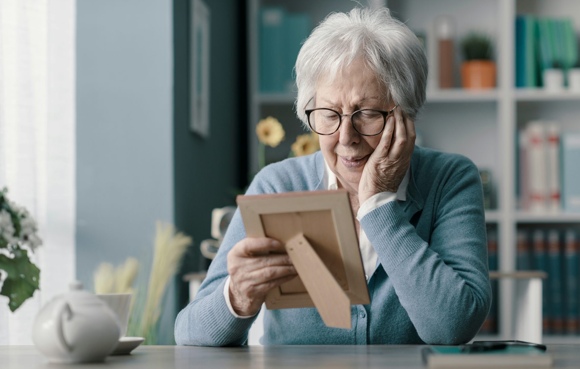 Photo d’une femme âgée regardant pensivement une cadre contenant une photo