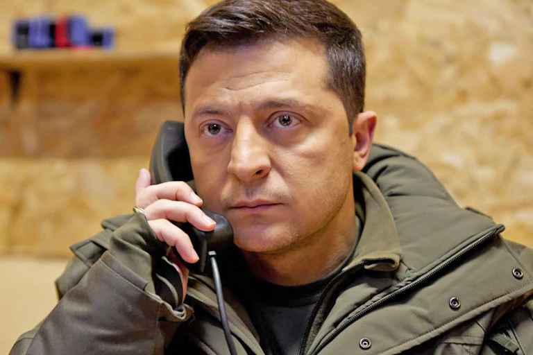 A man staring at the camera holding a telephone.