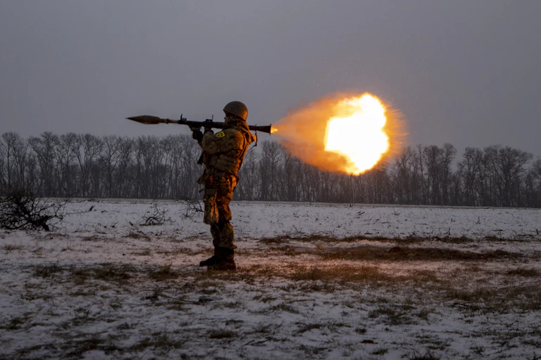 A ball of fire erupts after a solider fires his weapons that is held on his shoulder.