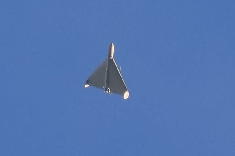 a small light gray delta wing aircraft against a clear blue sky
