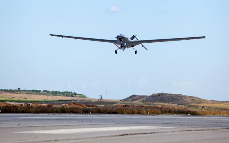 a small uncrewed aircraft flies just above a runway