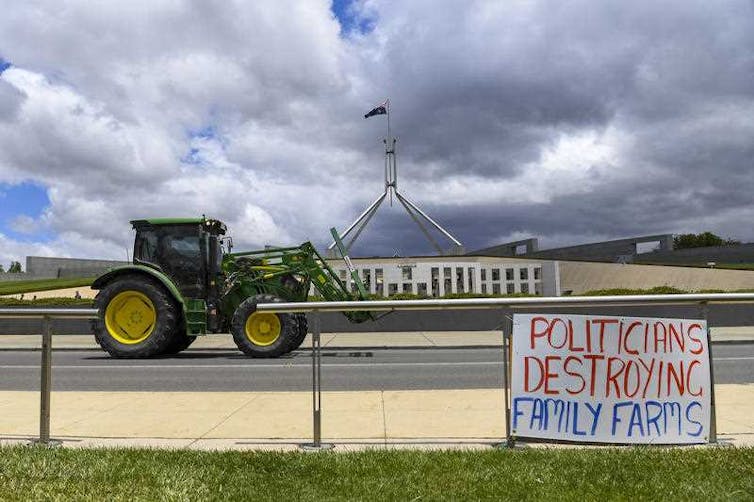 A tractor is seen parked near a sign saying Politicians Destroying Family Farms, outside Parliament House in Canberra, on Monday, December 2, 2019.