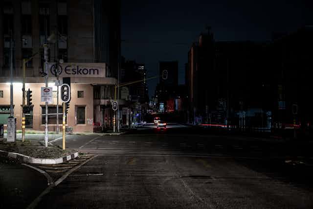 A dark street with just one light on at a building written Eskom