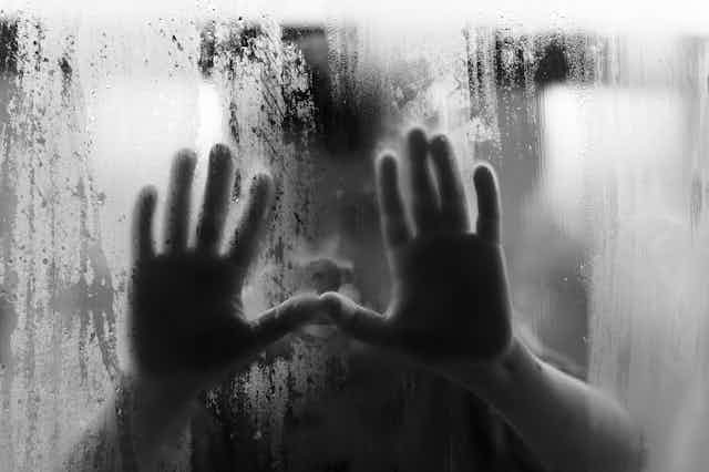 Child's hands on misted window