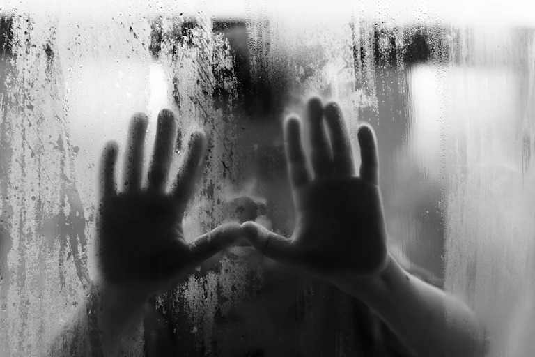 Child's hands on misted window