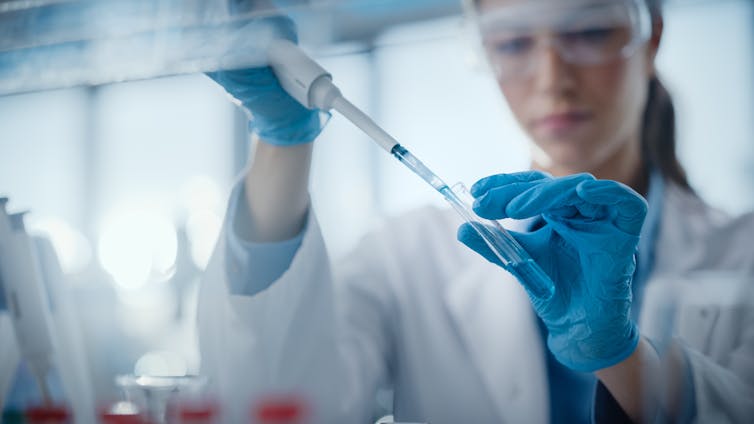 Scientists filling test tubes with a pipette.