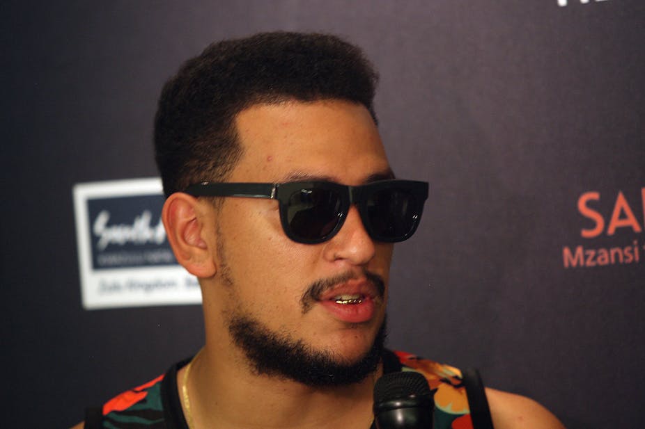 A man wearing sunglasses speaks into a microphone.