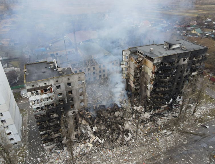 Damaged buildings with smoke overhead.