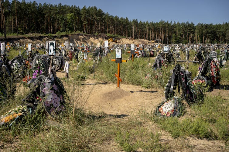 Cientos de tumbas cubren un parche de arena y maleza en un cementerio.
