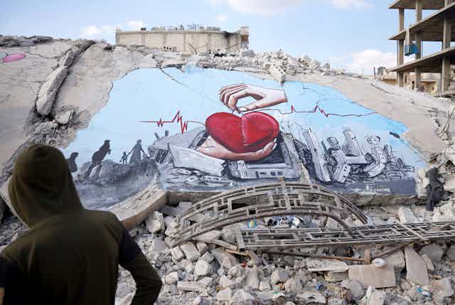 A mural of hands and a heart brighten up a bleak pile of rubble.