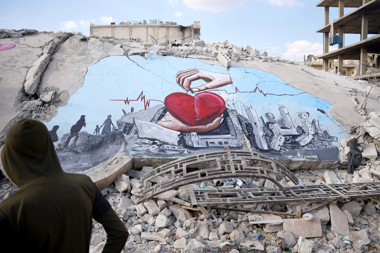 A mural of hands and a heart brighten up a bleak pile of rubble.