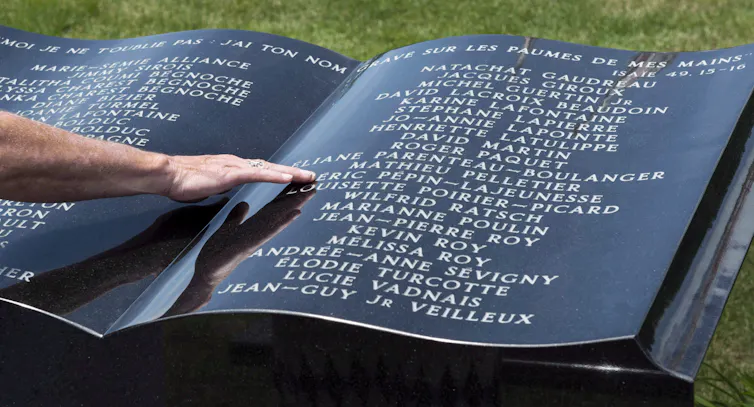 Un homme touche un monument en pierre qui ressemble à un livre géant