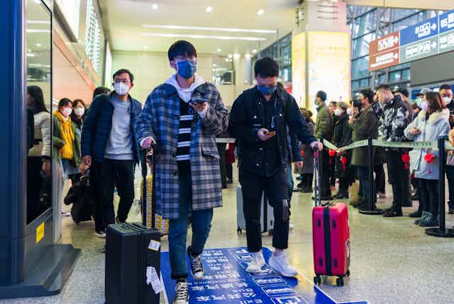 Masked students wheeling their suitcases through a Chinese airport