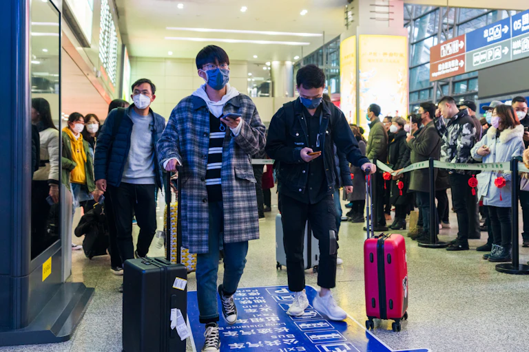 Masked students wheeling their suitcases through a Chinese airport