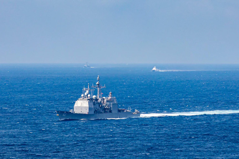 A ship moves across an expanse of water.