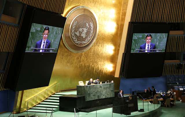A Chinese man speaks on two monitors at a session of the United Nations in New York.