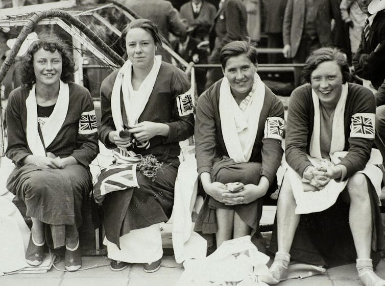 Four women in swimming robes, seated.