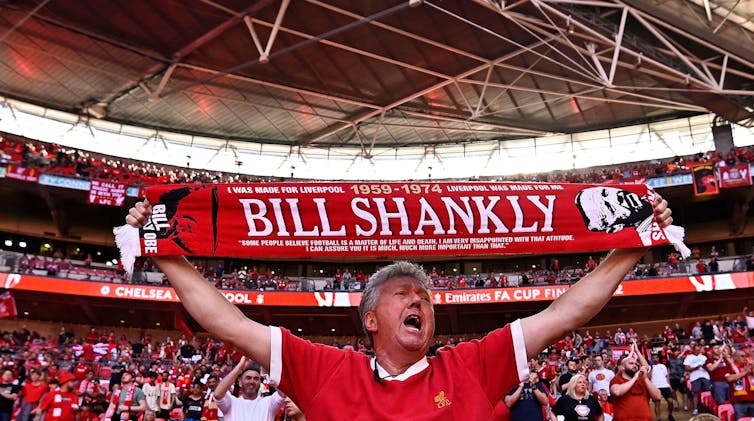 Fan in kit holding a football scarf.
