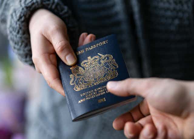 Two hands holding a dark blue passport.