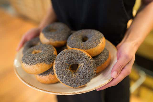 Person holding plate of poppy seed bagels